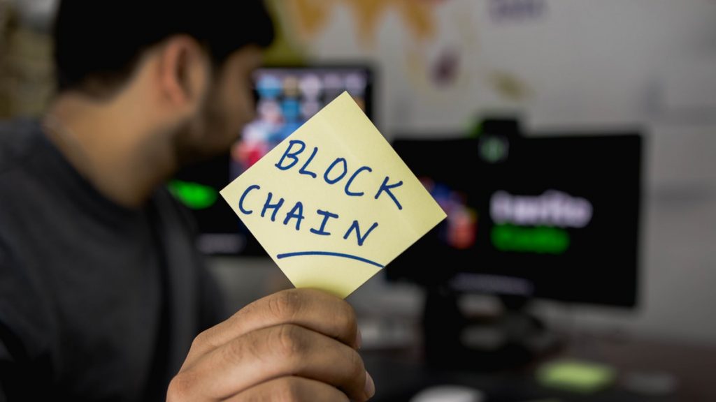 A guy holding a Blockchian card