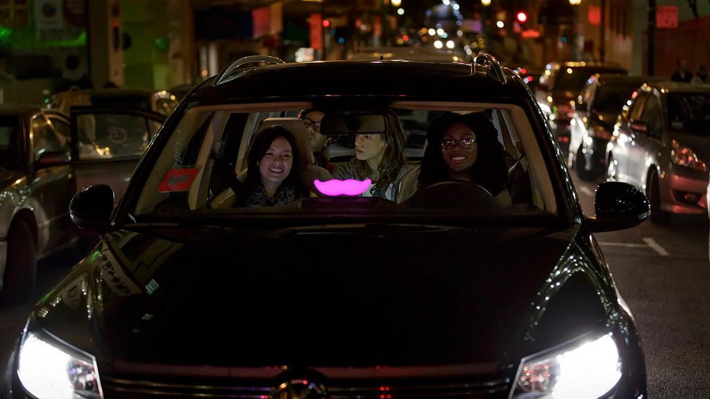 Passengers inside a car with Lyft's brand sign 