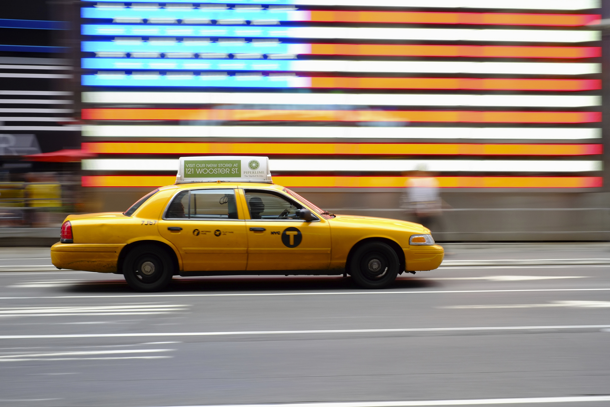 Yellow Taxi in NYC and a US flag in the background