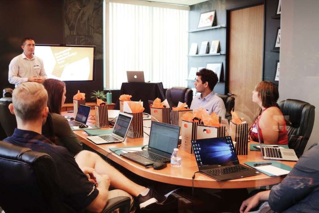 A team in an office discussing self-service knowledge bases during a meeting