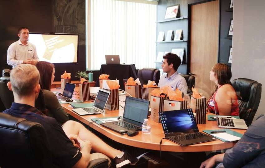 A team in an office discussing self-service knowledge bases during a meeting